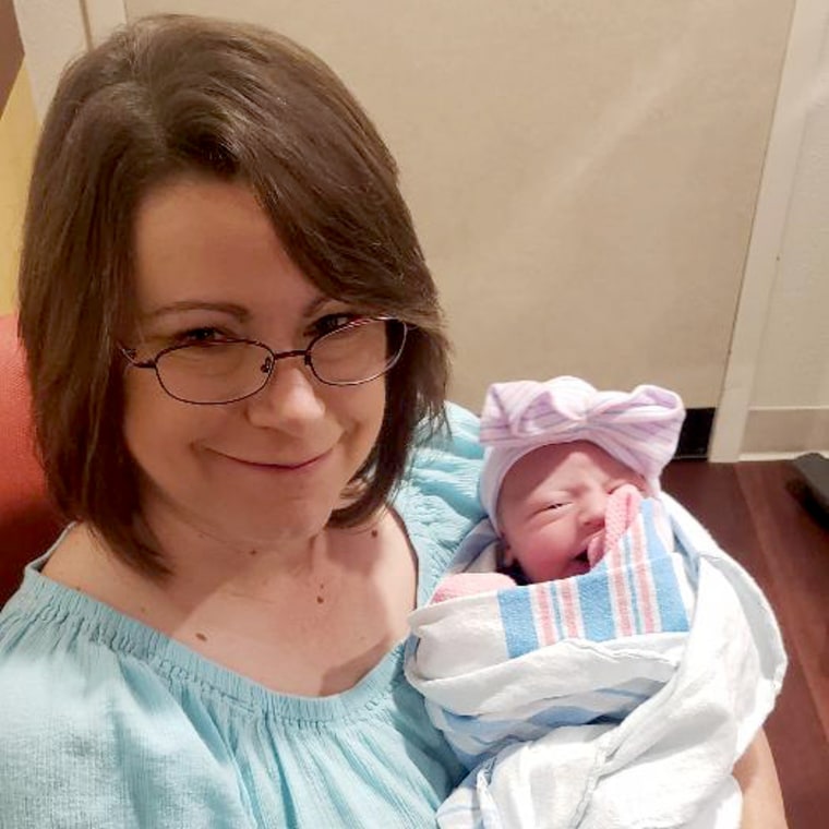 الصورة: كاثي جرينينجر تحمل حفيدتها المولودة حديثًا سافانا.